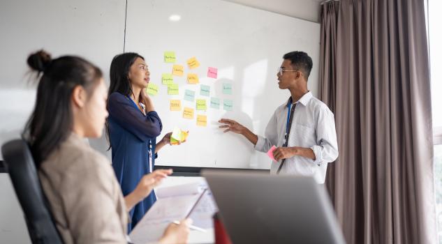 Colleagues discussing start up business ideas with sticky notes board.