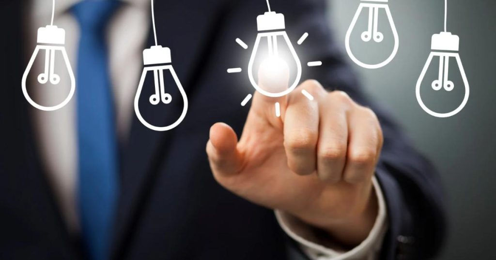 Businessman in a suit touching a glowing light bulb icon among several others, symbolizing innovation, creativity, and choosing the best idea.